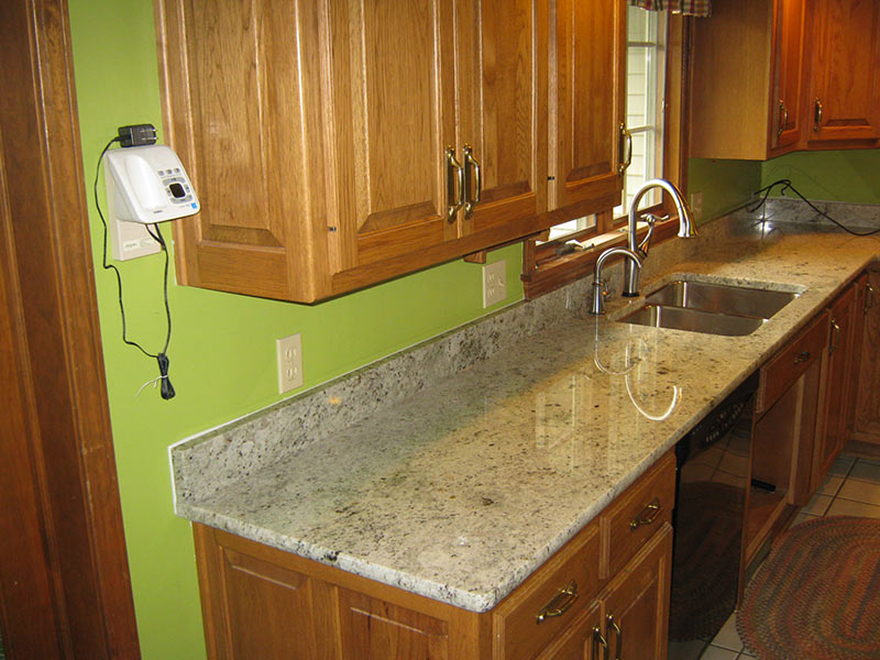 Colonial White Granite kitchen counter with medium brown cabinets.