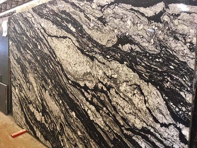 Movement of several shades of cream and gray through a black stone.